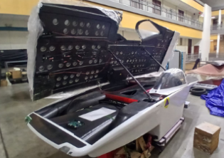 Solar race car in the Rice shop with the canopy open and the battery pack visible in the nose.